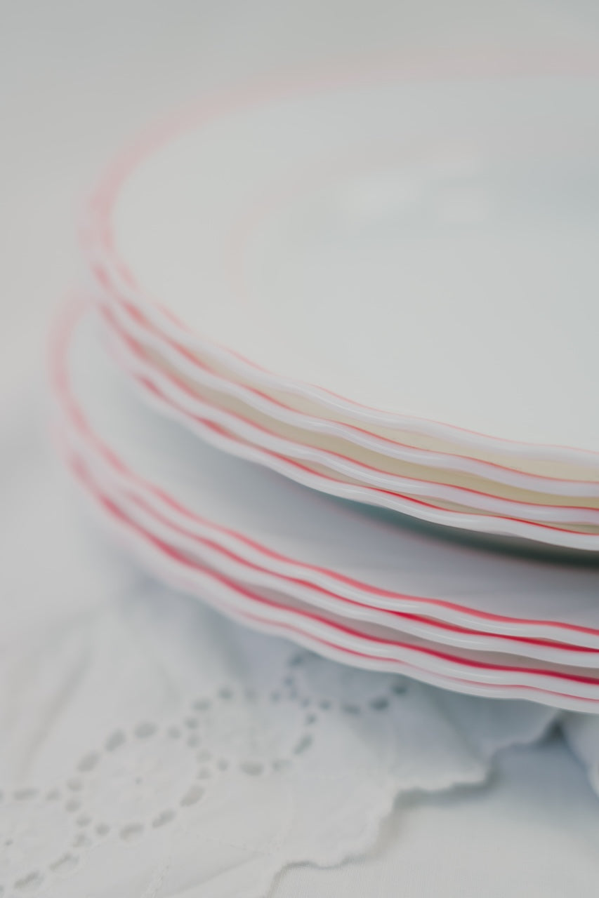 eight white plates with red rim