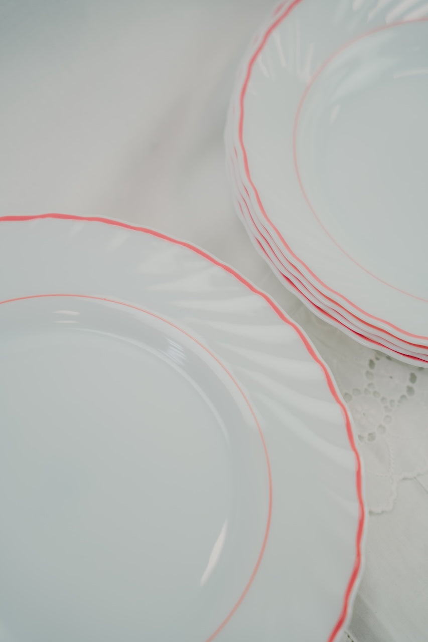 eight white plates with red rim