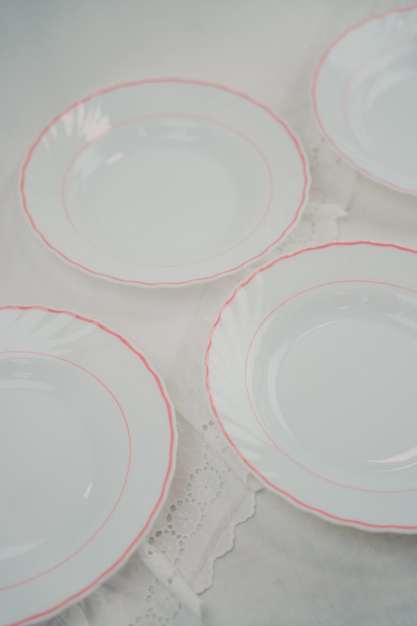 eight white plates with red rim