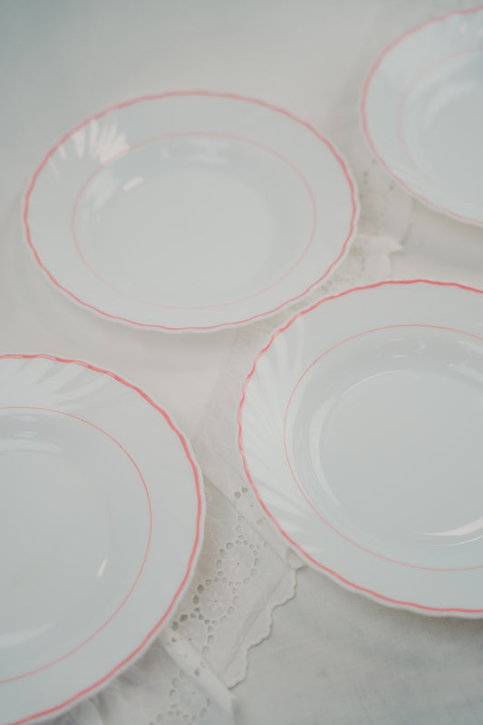 eight white plates with red rim