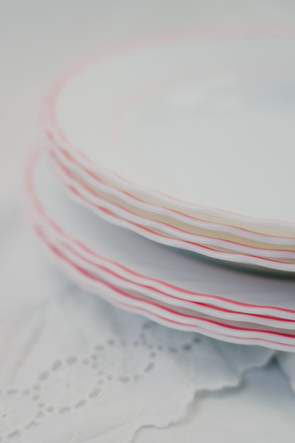 eight white plates with red rim