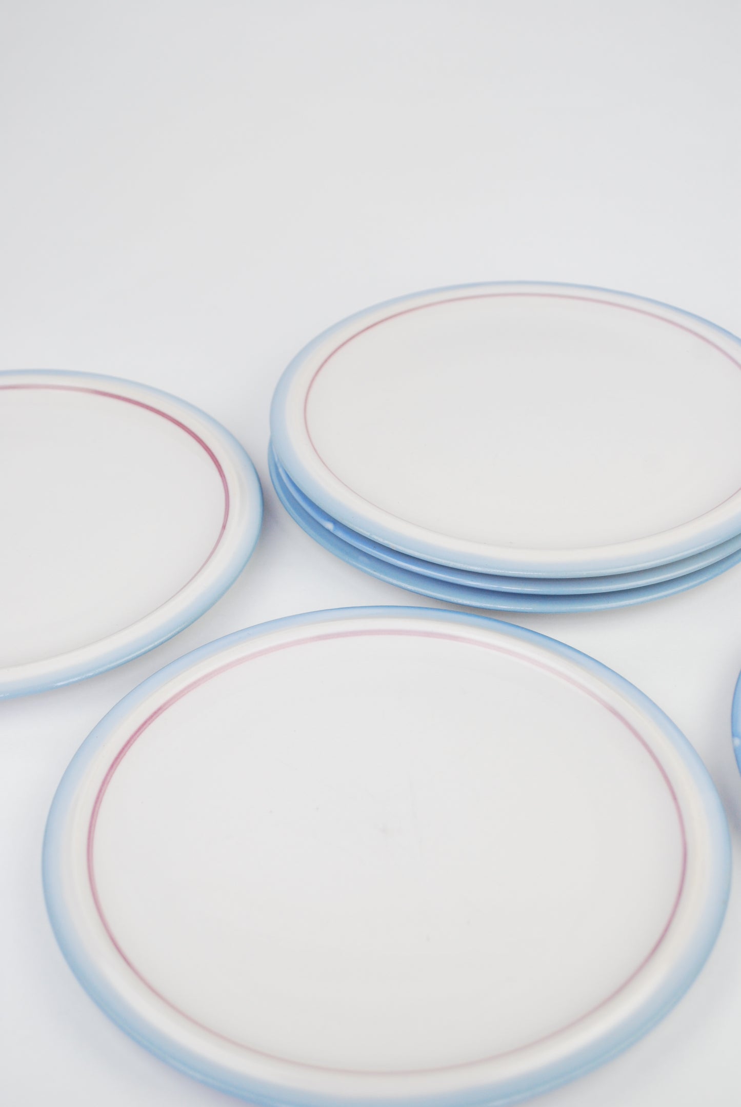 six white plates with blue and purple rim