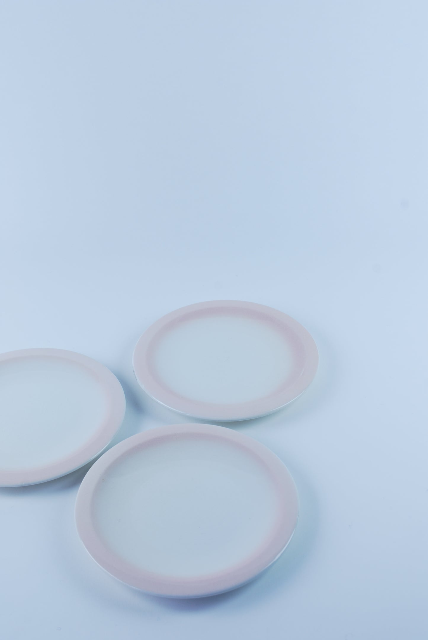 three white plates with pink rim