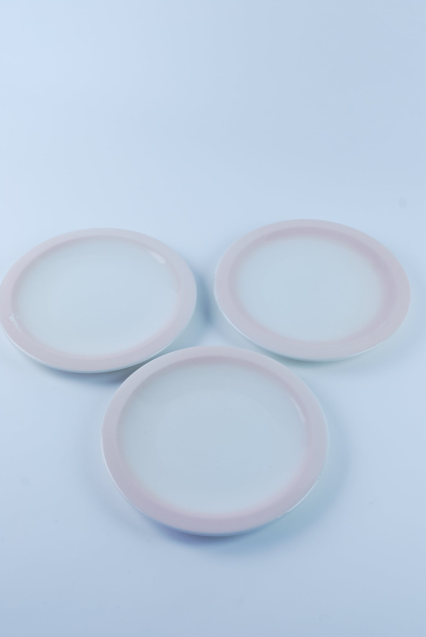 three white plates with pink rim