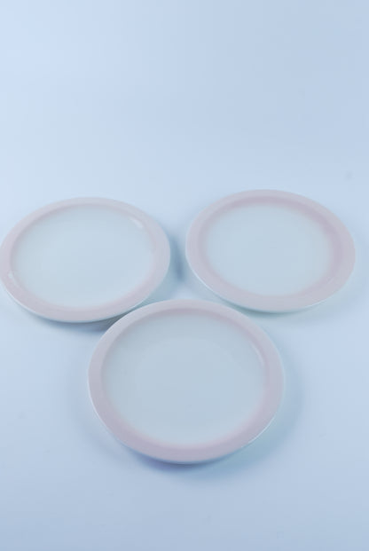 three white plates with pink rim